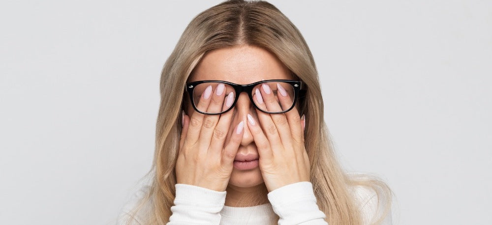 woman touching her eyes under her glasses