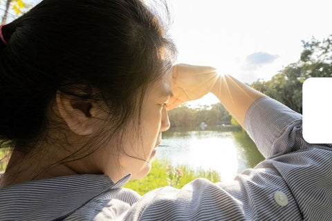 asian woman shielding her eyes from bright sunlight
