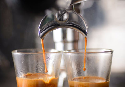 Zwei Tassen Espresso werden unter einer Kaffeemaschine abgefüllt