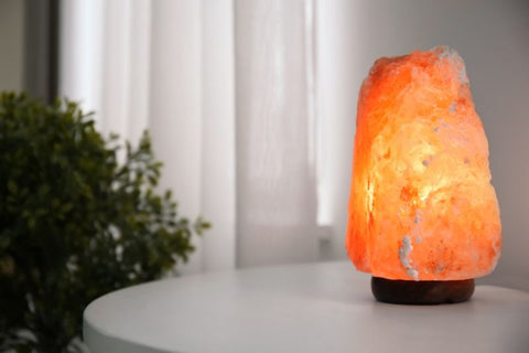 himalayan salt lamp on a bed side table