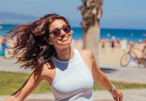 Junge glückliche Frau am Strand mit Sonnenbrille
