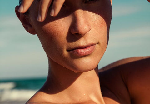 young woman dazzled by the sun covers her eyes with her arm