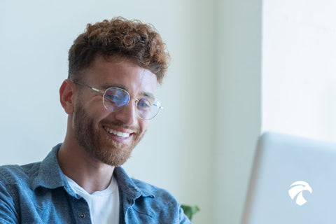 Modèle horus x devant son écran d'ordinateur et équipé de lunettes rondes anti lumière bleue