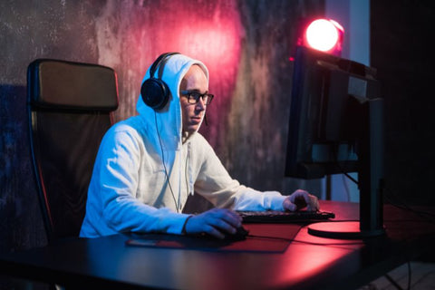 Gamer avec écouteurs et lunettes gaming jouant devant son écran