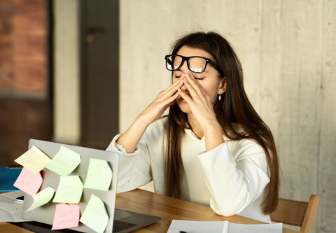 Femme qui se frotte les yeux à cause de la lumière devant son pc