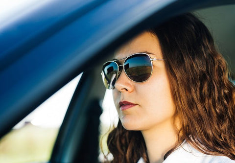 Junge Frau hinter dem Lenkrad mit aufgesetzter Sonnenbrille, um zu fahren