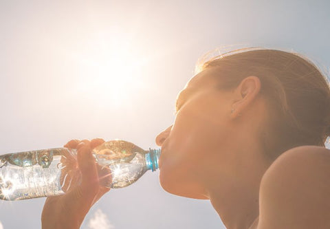 Une femme boit de l'eau sous le soleil