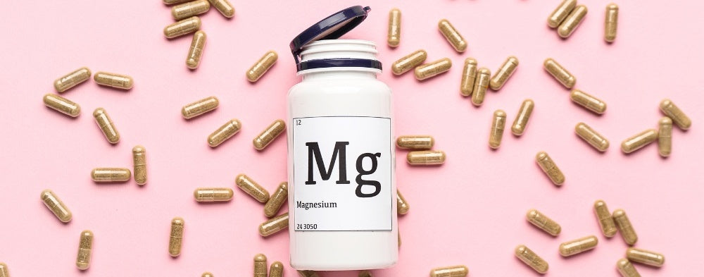 une bouteille avec des capsules de magnésium sur fond rose