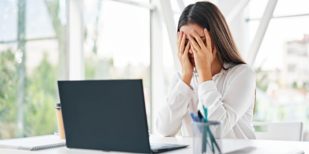 woman covering eyes at laptop screen