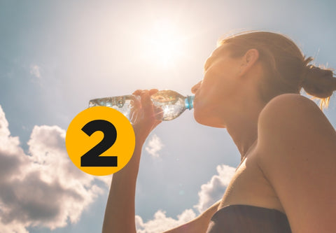 une femme boit de l'eau au soleil