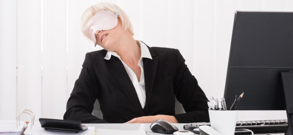 une femme d'affaires portant un masque pour les yeux et dormant
