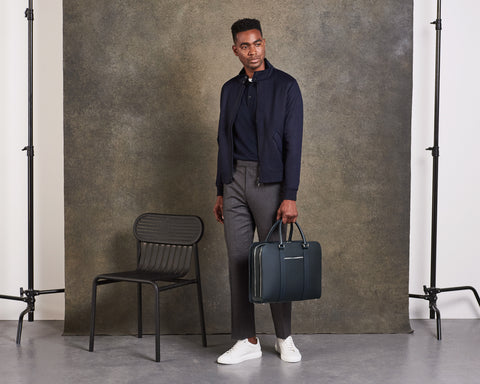 Male model walking with carry-on suitcase and navy leather briefcase