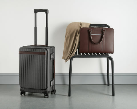 Polycarbonate suitcase and brown leather briefcase on a chair