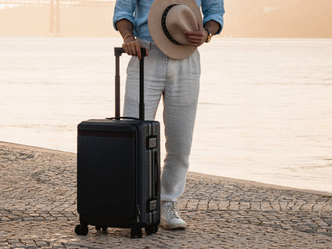 Carry-on suitcase beside man overlooking the sea