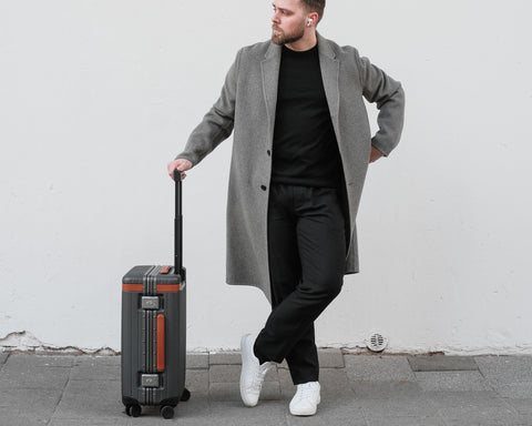 Stylish man holding Carl Friedrik hard-shell polycarbonate suitcase