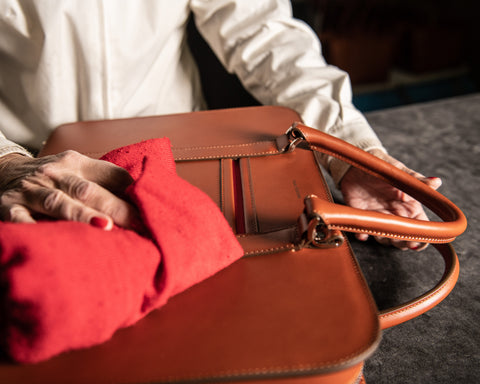 Leather worker cleaning an Italian leather briefcase with microfibre cloth