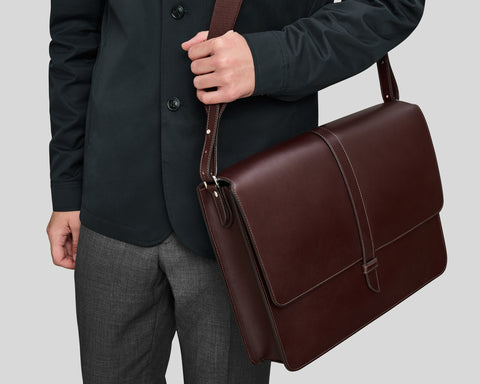 Man holding brown leather messenger bag