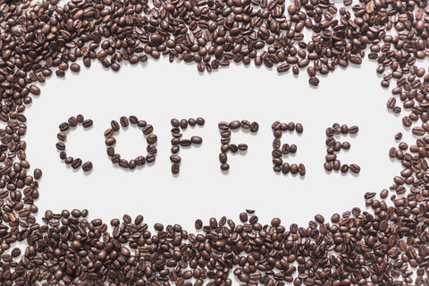 coffee beans on white background arranged so they spell out the word coffee