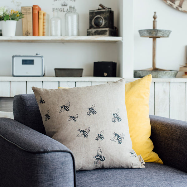 Bee Linen Cushion from the Honey Bee Collection & Mustard Linen Cushion from the Hedgerow Collection by Helen Round on a comfy chair