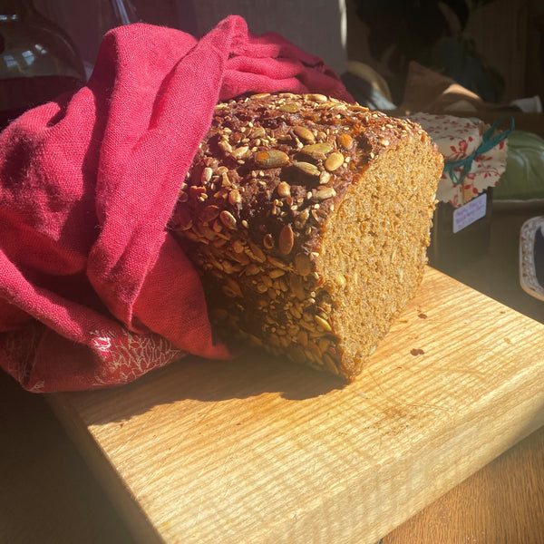 Seeded Rye Bread on Bread Board With Raspberry Red Linen Bread Bag from Helen Round