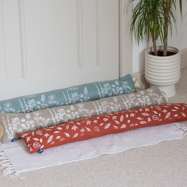 Three Linen Draught Excluders on a white rug by a door from Helen Round