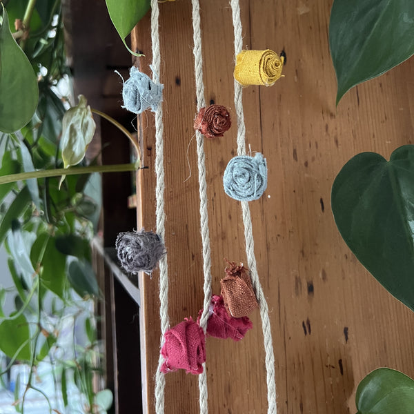 Multi - coloured Linen Rose Garland hanging vertically from shelves