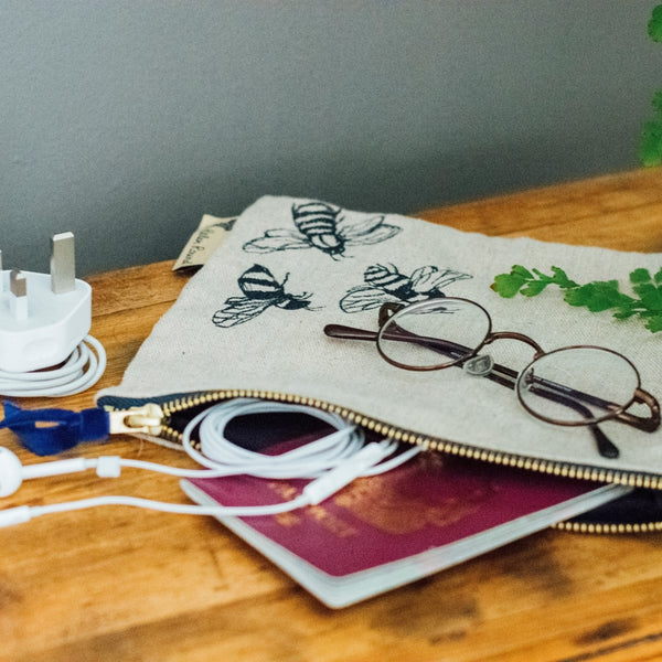 Useful Pouch with Bee Design on table next to charger, glasses and passport