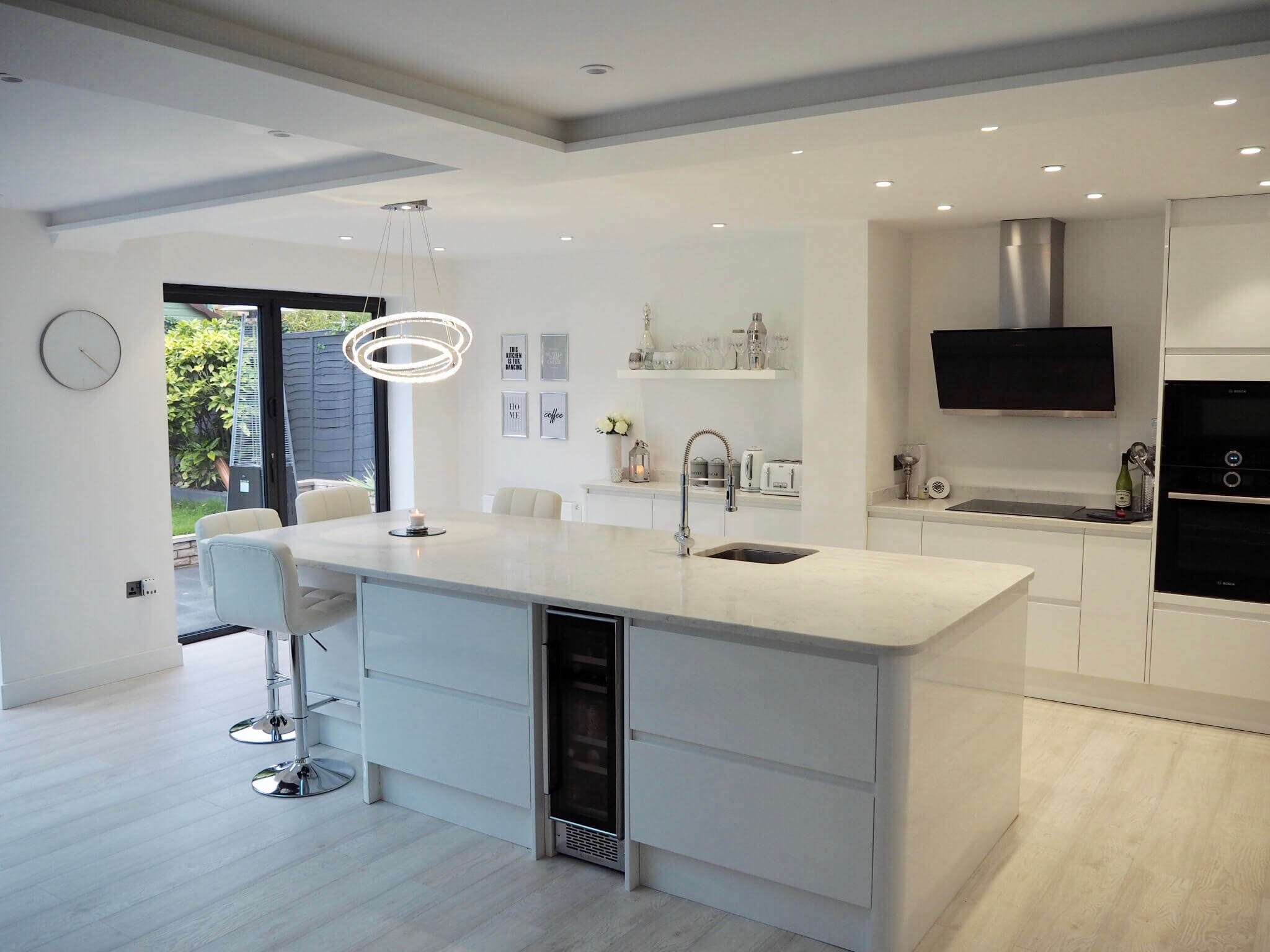 A white, bright and modern contemporary kitchen with bifolding doors.