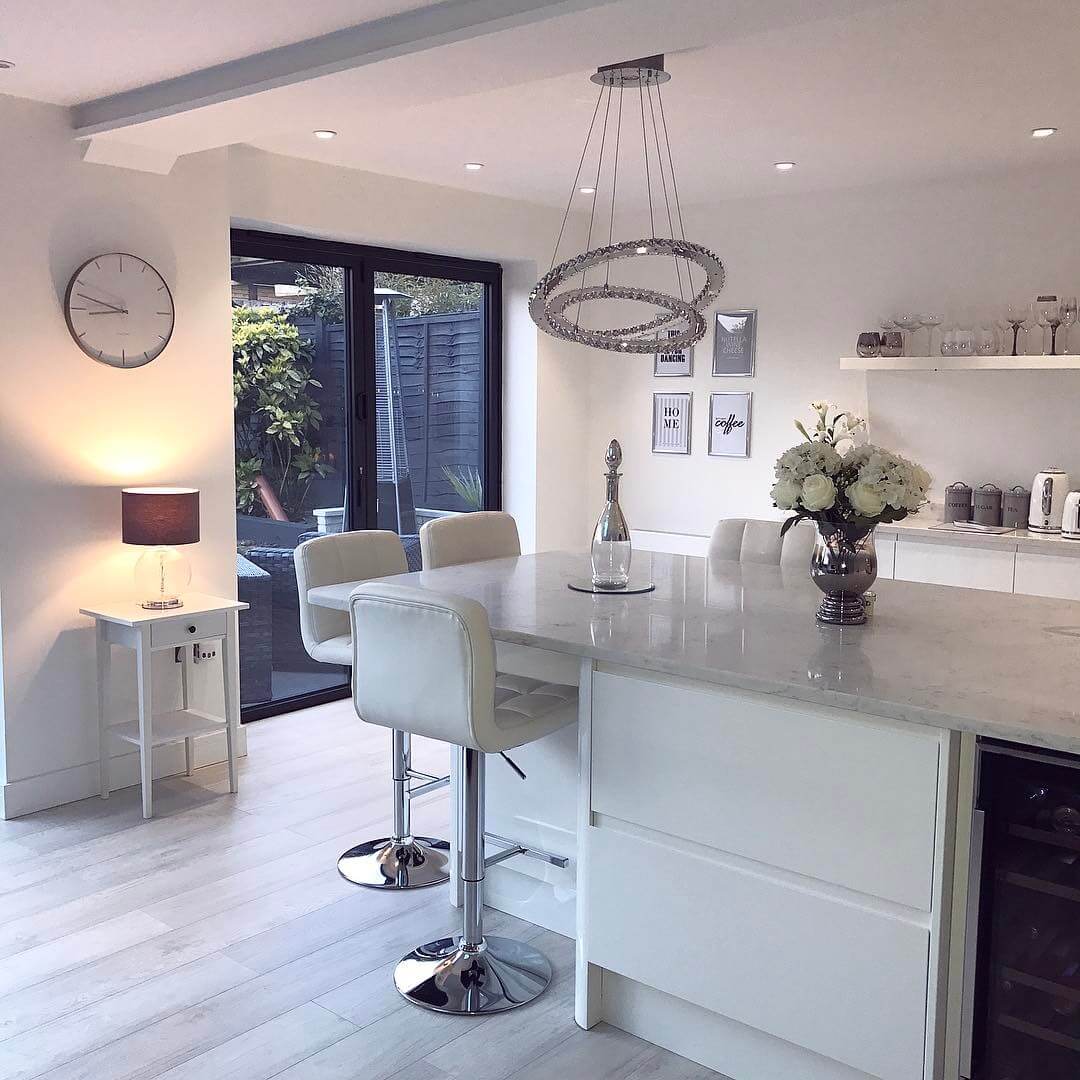 Softly lit Scandinavian inspired white modern contemporary open plan kitchen living room with bi folding doors.