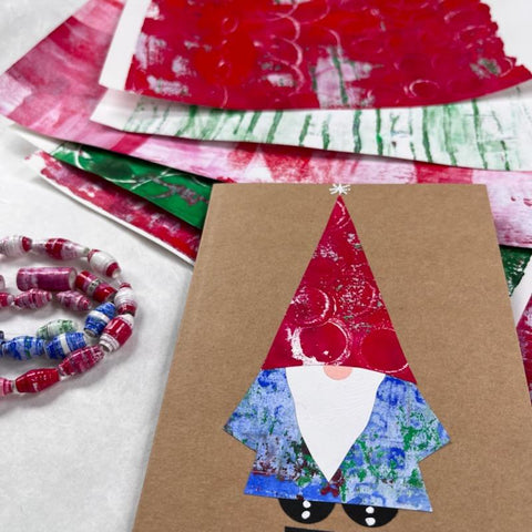 kraft paper card with a collaged gnome and a stack of colored papers in the background