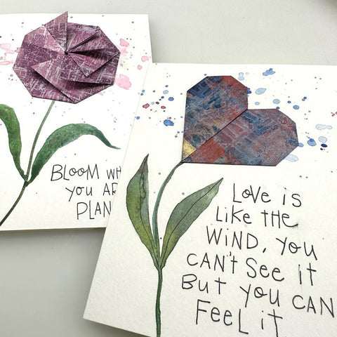 two cards with origami embellishments and handwritte quotes: "Bloom where you are planted" and "Love is like the wind, you can't see it but you can feel it"