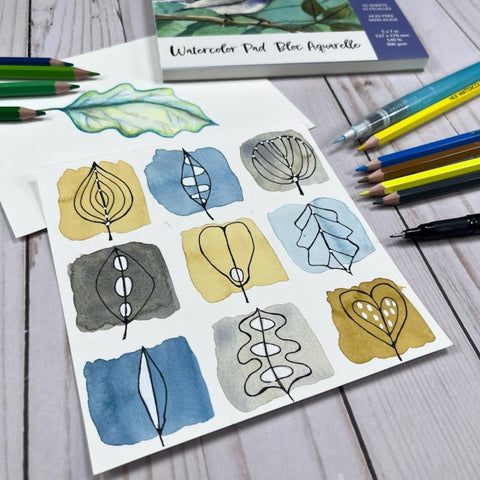 pen drawn leaf doodles on top of watercolor squares with watercolor paper, watercolor pencils and waterbrushes around