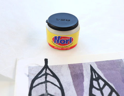 a jar of nori paste next to a collage with leaf designs