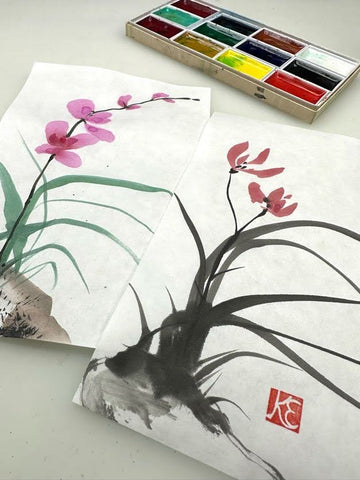 two gansai orchid paintings with a gansai watercolor set in the backgroun