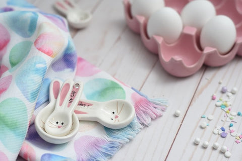 Bunny measuring spoons next to a pink egg carton and colourful sprinkles