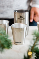 Stanley cocktail shaker with two stainless-steel shot glasses on a table.