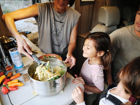 Mother with family in RV making pasta with Stanley's stainless-steel, Even-Heat Camp Pro Cook Set.