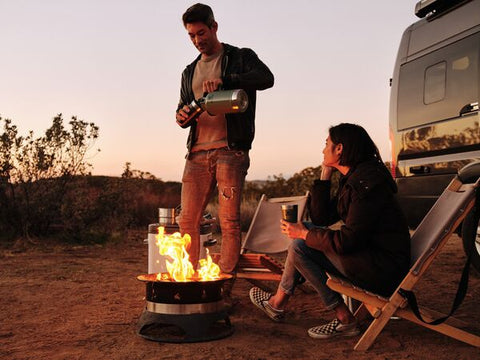 Man standing next to campfire, serving beer from Stanley's insulated Easy-Pour Growler in Hammertone Green.