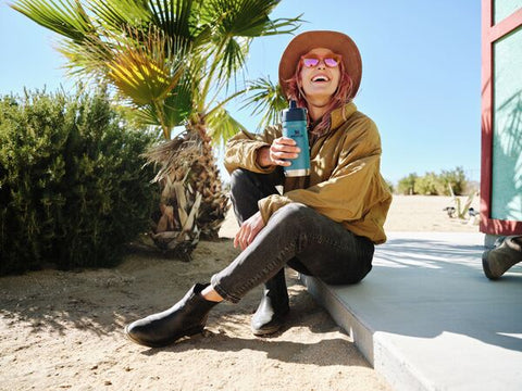 Woman at the beach with her Stanley IceFlow™ Flip Straw Water Bottle in Lagoon.