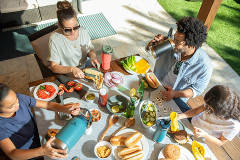 Mother with family enjoying a backyard picnic with colorful drinkware from Stanley's IceFlow™ Flip Straw Collection.
