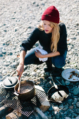 Woman cooking by campfire