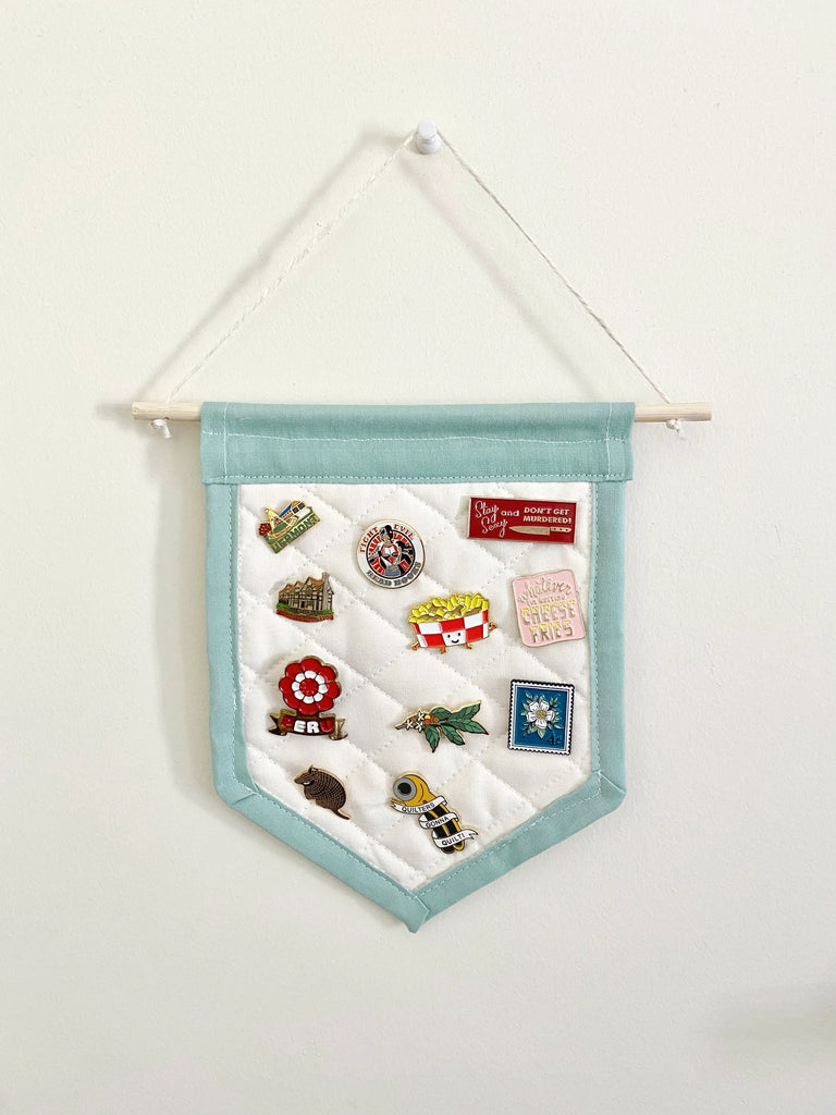 Mini banner enamel pin display hanging on wall.