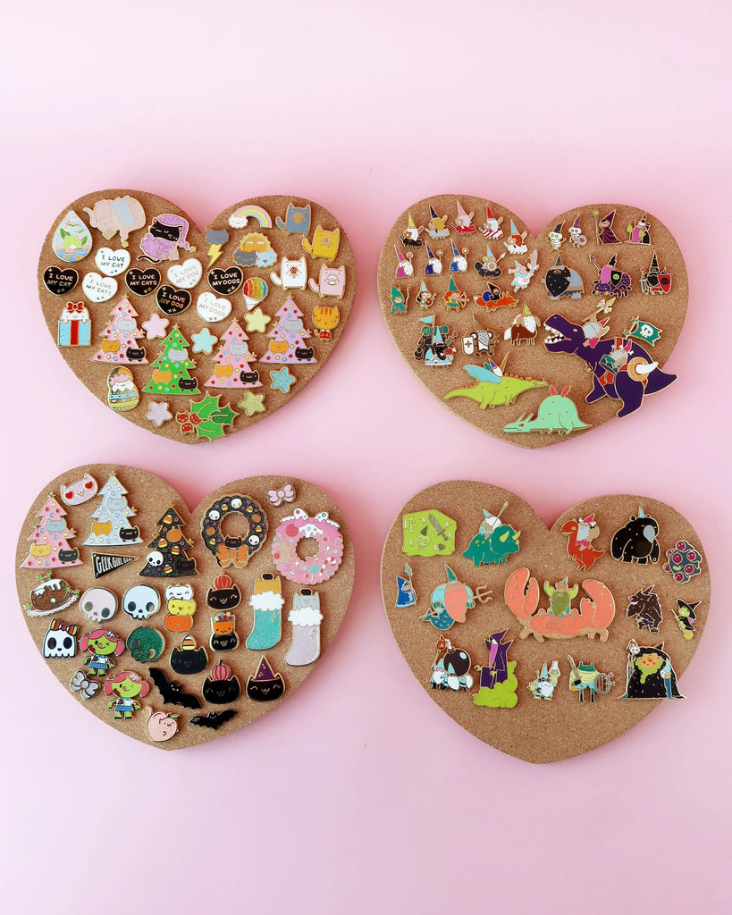 Four heart shaped cork boards with enamel pins.