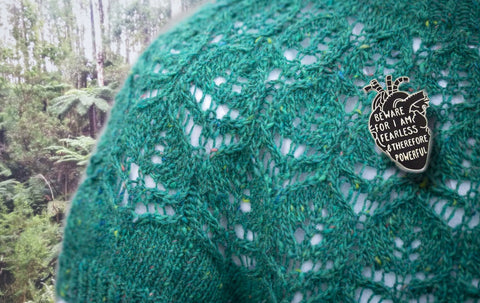 Lace jumper in bright green nephrite tweed yarn with a enamel badge with a quote saying “Beware for I am fearless & therefore powerful”