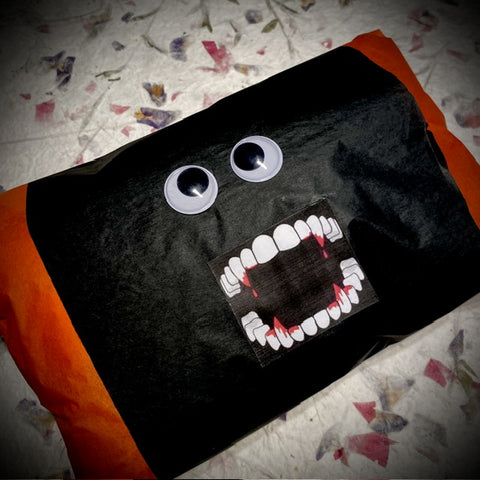 Parcel packed in teh shape of a monster with googlyeyes and fangs