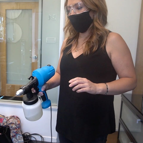 hair salon owner uses a disinfectant fogger to disinfect her hair salon while wearing mask and gloves
