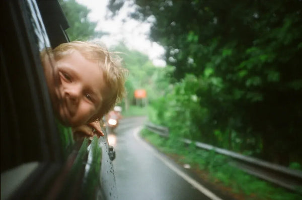 image of happy child in a car with head poking out of back window