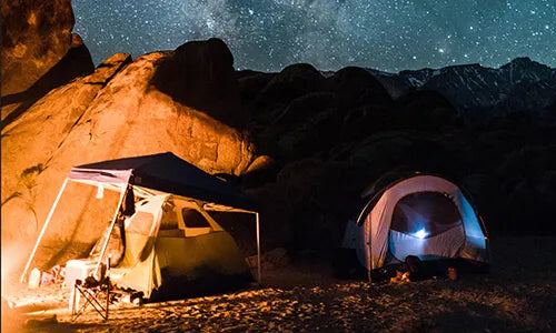 image of a camp in a desert on a warm nite with stars in the background