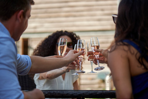 A group 'cheers' their wine glasses outside at the Chapel Down winery