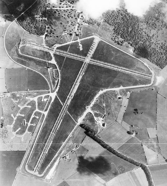 Aerial photograph of Chedworth airfield looking north, the control tower and airfield code are to the top left of the runway intersection, 7 June 1946